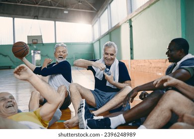 Senior men sitting on basketball court floor after playing - Powered by Shutterstock