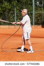 Senior men sprinklig tennis court before playing - Shutterstock ID 577442686
