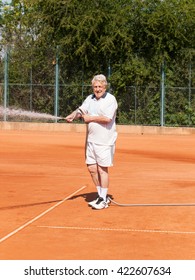 Senior men sprinkling tennis court before playing - Shutterstock ID 422607634