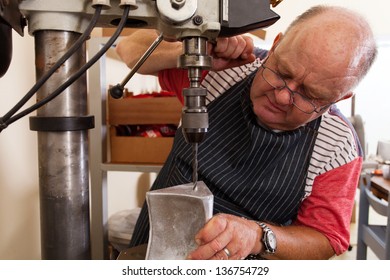 senior metal worker using industrial drilling machine in workshop - Powered by Shutterstock