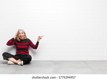 senior middle age pretty woman laughing  looking happy  positive   surprised  realizing great idea pointing to lateral copy space