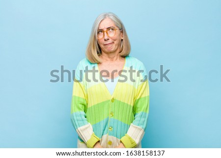 senior or middle age pretty woman looking goofy and funny with a silly cross-eyed expression, joking and fooling around
