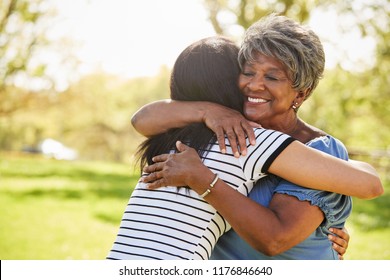 Senior Mother With Adult Daughter Hugging In Park