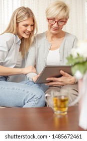 Senior Mother And Daughter Browsing The Internet On A Tablet. Happy Family Moments At Home.