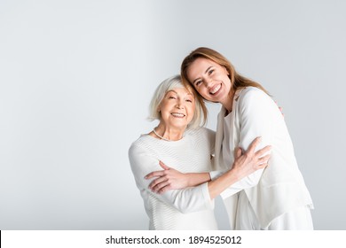 Senior Mother Hugging With Happy Daughter Isolated On Grey