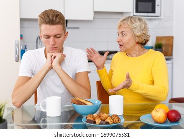 Senior Mother Lecturing Her Sad Adult Son At Kitchen