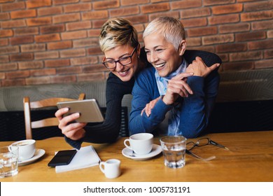 Senior Mother Sitting In Cafe Bar Or Restaurant With Her Middle Age Daughter And Enjoying In Conversation.