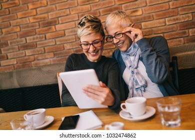 Senior Mother Sitting In Cafe Bar Or Restaurant With Her Middle Aged Daughter And Enjoying In Conversation. 