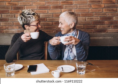 Senior Mother Sitting In Cafe Bar Or Restaurant With Her Middle Age Daughter And Enjoying In Conversation.