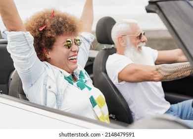 Senior multiracial couple having fun with convertible car during road trip vacation - Powered by Shutterstock