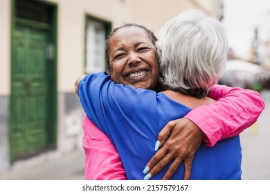 Senior multiracial female friends meeting and hugging each other in the city - Powered by Shutterstock