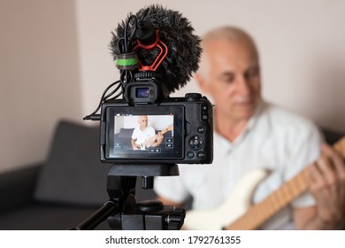 Senior Music Teacher Recording Guitar Lesson At Home On Video