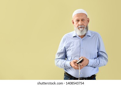 Senior Muslim Man With Koran And Tasbih Against Color Background