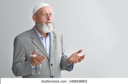 Senior Muslim Man Praying Against Light Background