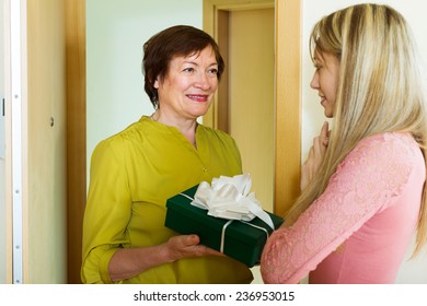 Senior Neighbor Presenting A Gift In Box To Young Girl 