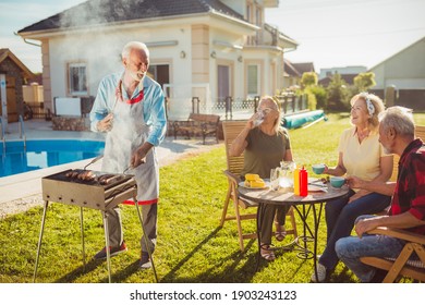 Senior Neighbors Having Fun Spending Sunny Summer Day Together Outdoors, Having A Backyard Barbecue Party By The Swimming Pool