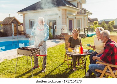 Senior Neighbors Having Fun Spending Sunny Summer Day Together Outdoors, Having A Backyard Barbecue Party By The Swimming Pool