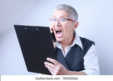 Senior Old Business Woman Yelling On Her Phone, Unhappy With A Financial Report She's Reading