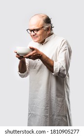 Senior Or Old Indian Asian Man Eating From Empty White Plate Or Bowl Using Spoon And Fork - Standing Isolated Over White Background With Different Expressions