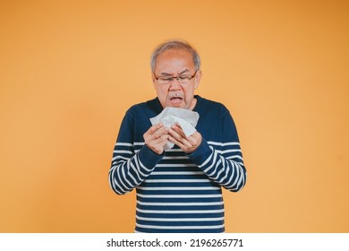 Senior Old Man Sneezing With Tissue, Asian Elderly Man Sick, Cold Having Fever And Flu Sinus From Sickness Virus Problem Use Tissue, Pensioner Unwell On The Yellow Background