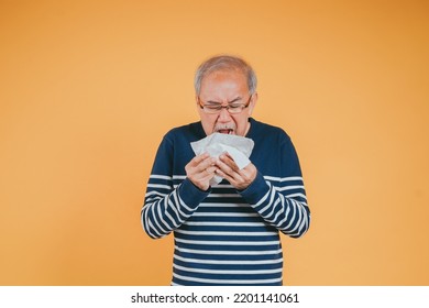 Senior Old Man Sneezing With Tissue, Asian Elderly Man Sick, Cold Having Fever And Flu Sinus From Sickness Virus Problem Use Tissue, Pensioner Unwell On The Yellow Background