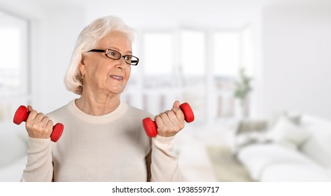 Senior Old Woman Lifting Weights And Working Out At Home.