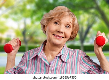 Senior Old Woman Lifting Weights And Working Out At Home.