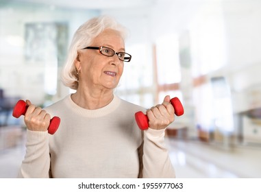 Senior Old Woman Lifting Weights And Working Out At Home.