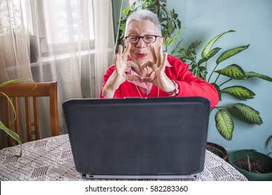 Senior Old Woman Sending Love And Kisses To Her Family Over Skype Or Viber Using Her Laptop