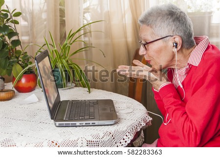 Senior old woman sending love and kisses to her family over Skype or Viber using her laptop