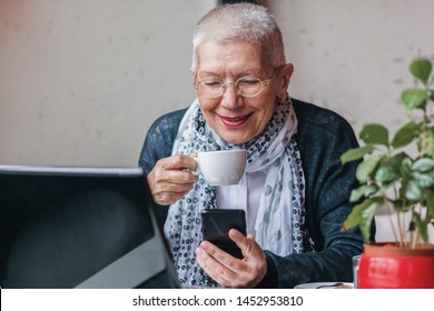 Senior old woman sitting in a coffee shop and having a nice chat over her cell phone - Powered by Shutterstock