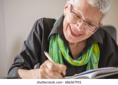 Senior old woman writing down letters on a piece of paper, recor