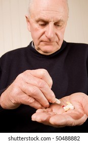 Senior Older Man Taking A Tablet Or Pill From A Group Of Many In His Hand