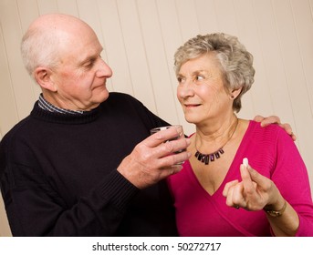 Senior Older Mature Couple Taking Pain Medication With Glass Of Water