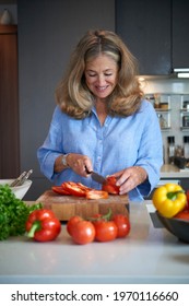 Senior Older Woman Chopping Vegetables In Modern Kitchen 