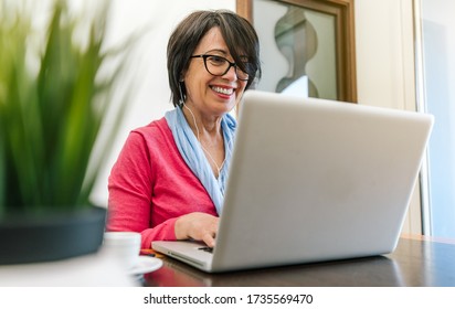 Senior Older Woman Working With Laptop Computer On The Table At Home Indoor. Old Mature People And Technology Concept