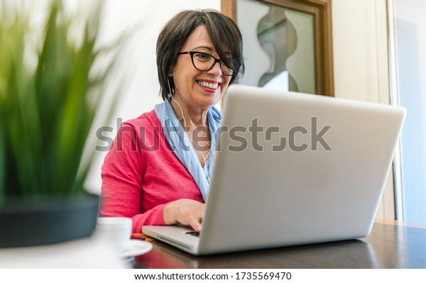Senior
older woman working with laptop computer on the table at home
indoor. Old mature people and technology
concept