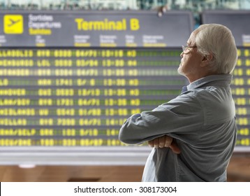 Senior On A Background Of Departure Board At Airport