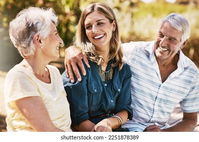 Senior parents in nature with their adult daughter sitting, talking and bonding together in a garden. Happy, love and elderly people embracing child with care, happiness and affection in outdoor park - Powered by Shutterstock