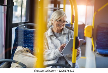 Senior Passenger Using Digital Tablet On A Bus