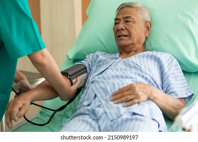 Senior Patient Lying On The Bed And Nurse Measuring Blood Pressure In The Hospital 