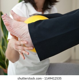 Senior Patient Undergoing Rehabilitation With A Yellow Ball