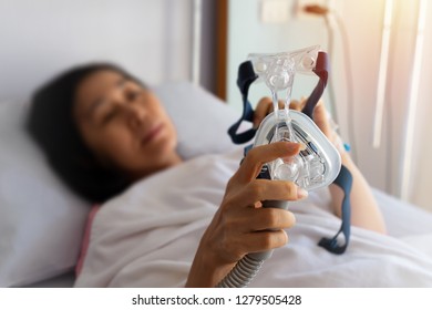 Senior Patient Woman Hands Holding Cpap Mask  Lying  In Hospital Room,selective Focused.
Obstructive Sleep Apnea Therapy.