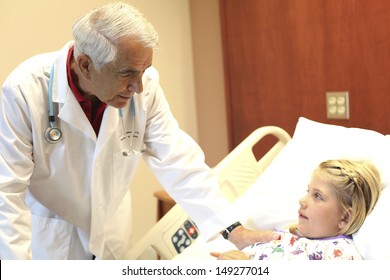 Senior Pediatrician Doctor Examining Girl In Clinic