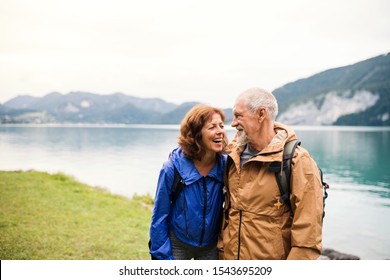 A senior pensioner couple walking by lake in nature, talking. - Powered by Shutterstock