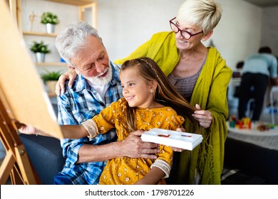 Senior people with child painting on canvas. Grandparents spending happy time with grandchild.