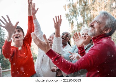 Senior people enjoying Happiness of first snow outdoors. Cheerful friends dancing with hands up while Snowing for winter Holidays. Close up - Powered by Shutterstock