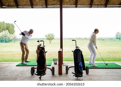 Senior people or golfers at golf course practicing long shots.