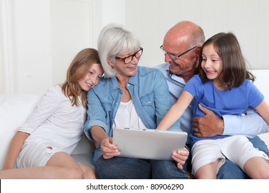 Senior People With Grand Kids Using Electronic Tablet