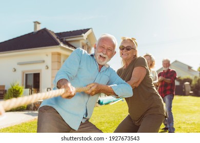 Senior People Having Fun Playing Tug Of War Game, Spending Sunny Summer Day Outdoors; Group Of Elderly Friends Having Fun Participating In Rope Pulling Competition